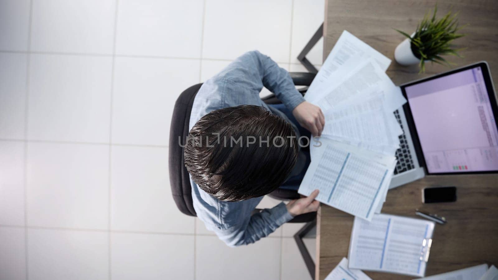 A male office worker is scattering papers.