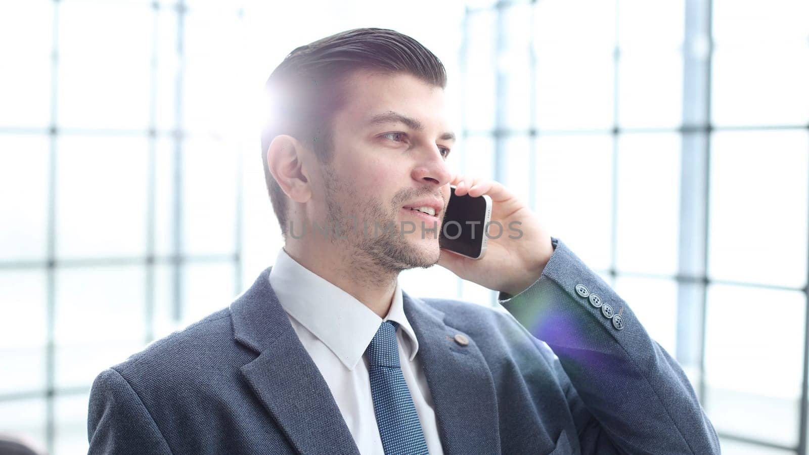 A businessman man in close-up in the office talking on the phone.