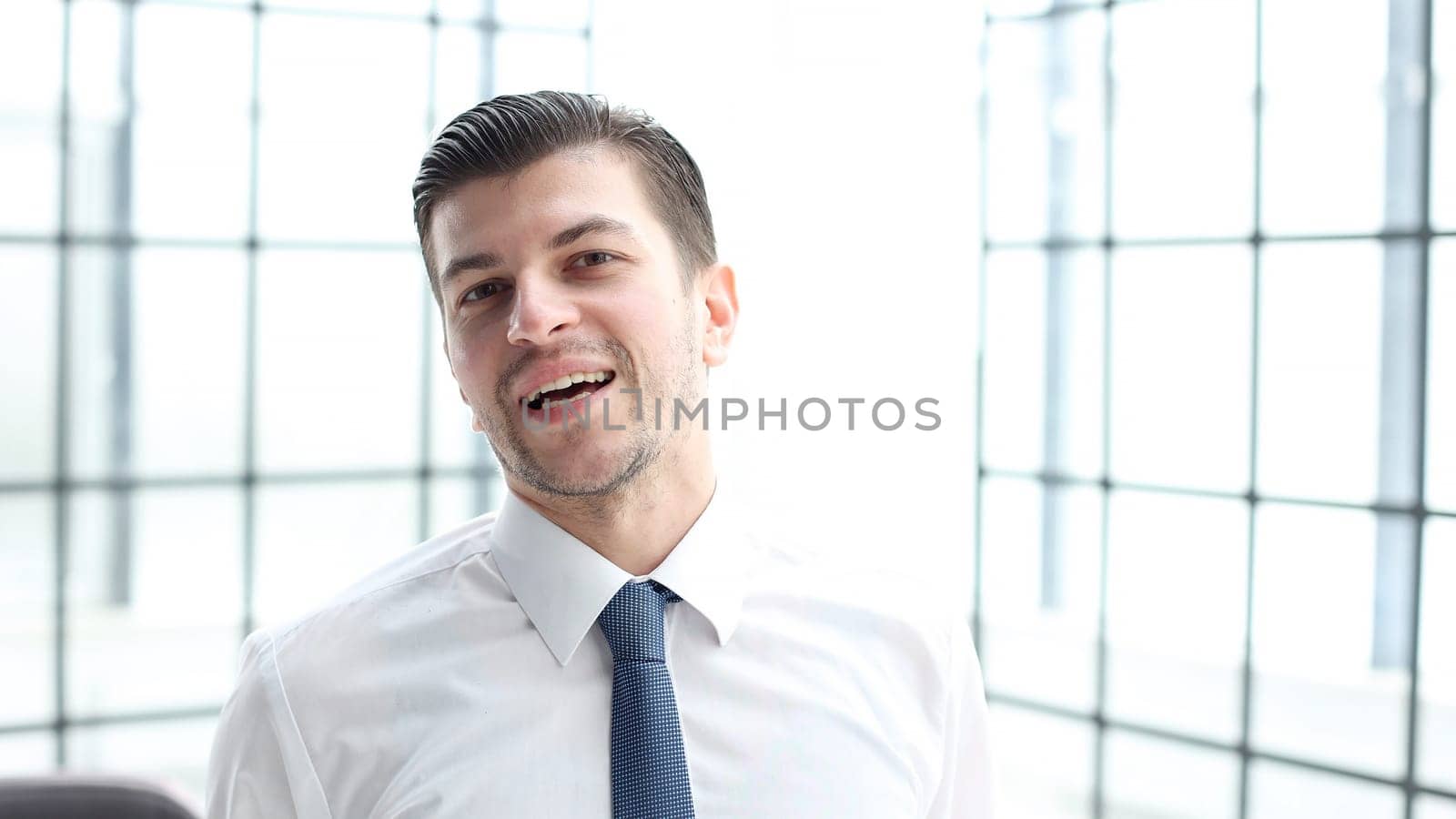 A male office worker looks at the camera in close-up.