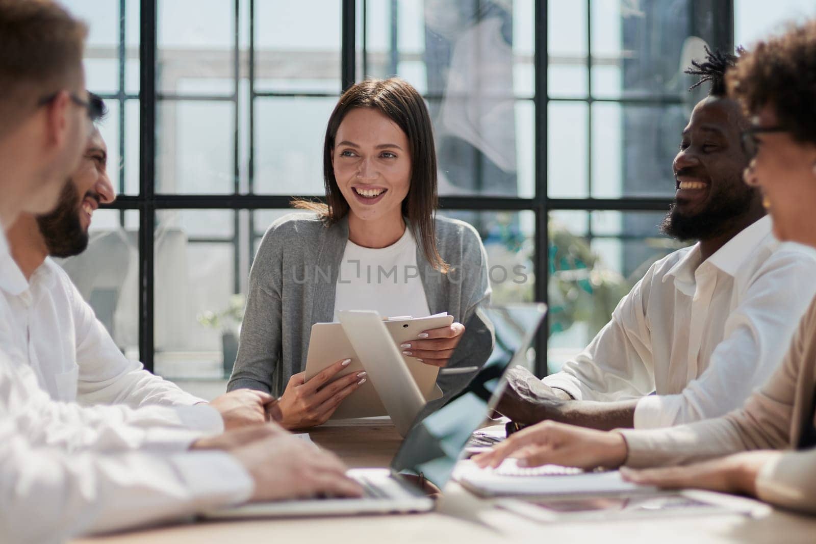 Happy young female employee discussing online project, showing computer presentation to skilled team leader in eyeglasses. Friendly diverse colleagues working in pairs on laptop, using applications.