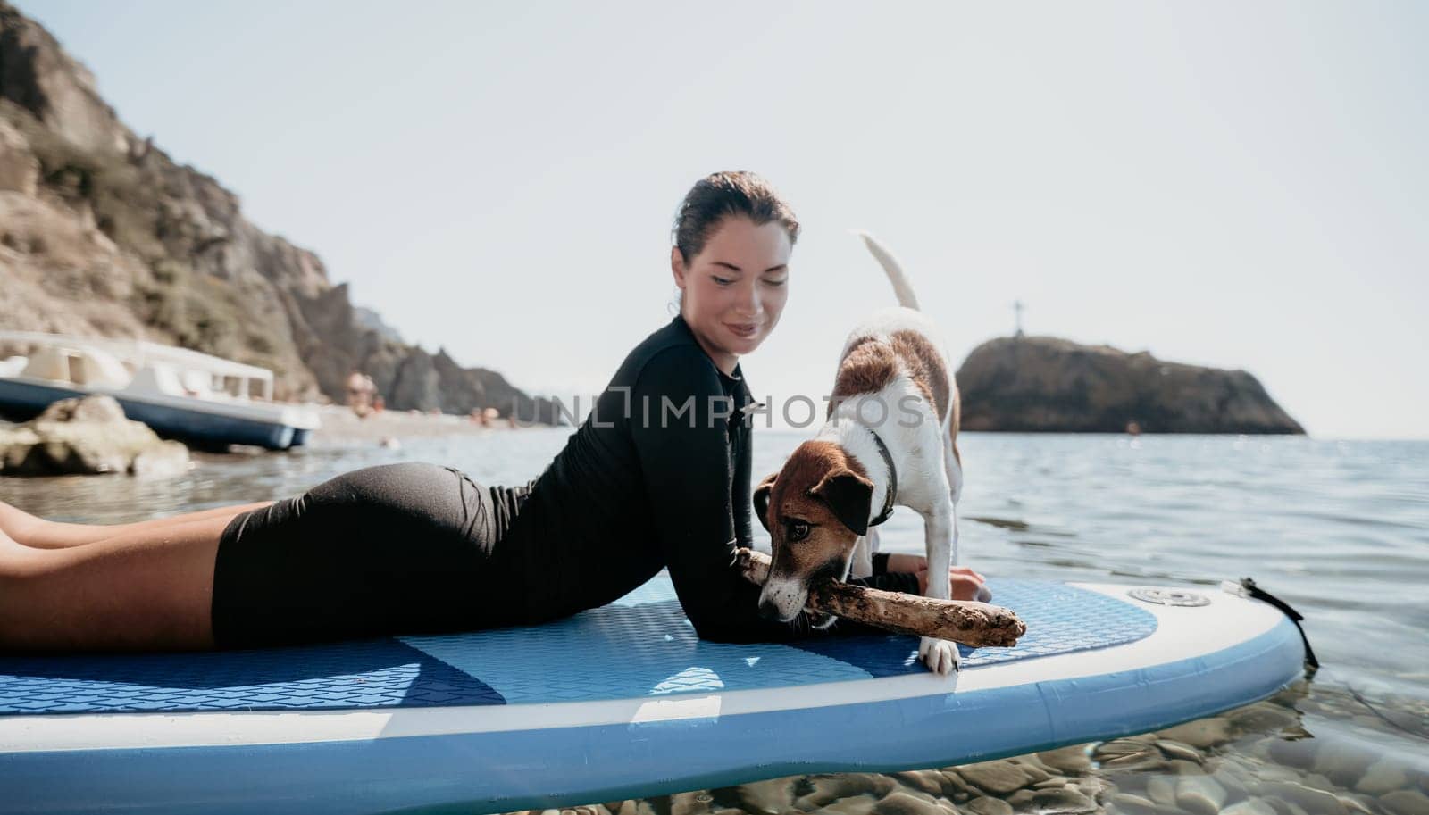 Sea woman sup. Silhouette of happy positive young woman with her dog, surfing on SUP board through calm water surface. Idyllic sunset. Active lifestyle at sea or river. Summer vacation with pets. by panophotograph