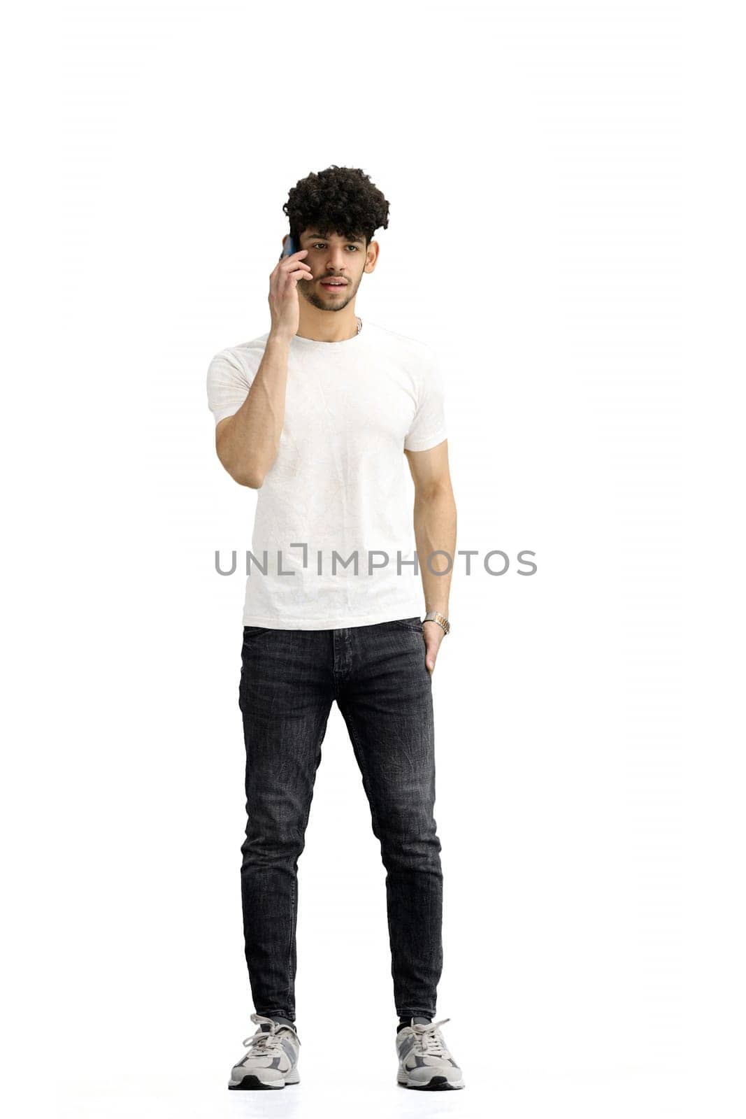 A man, on a white background, in full height, with a phone.