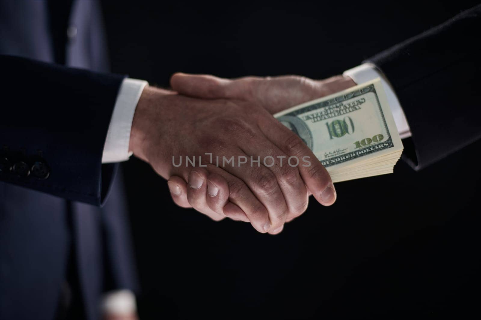 Handshake with the transfer of money on a black background by Prosto