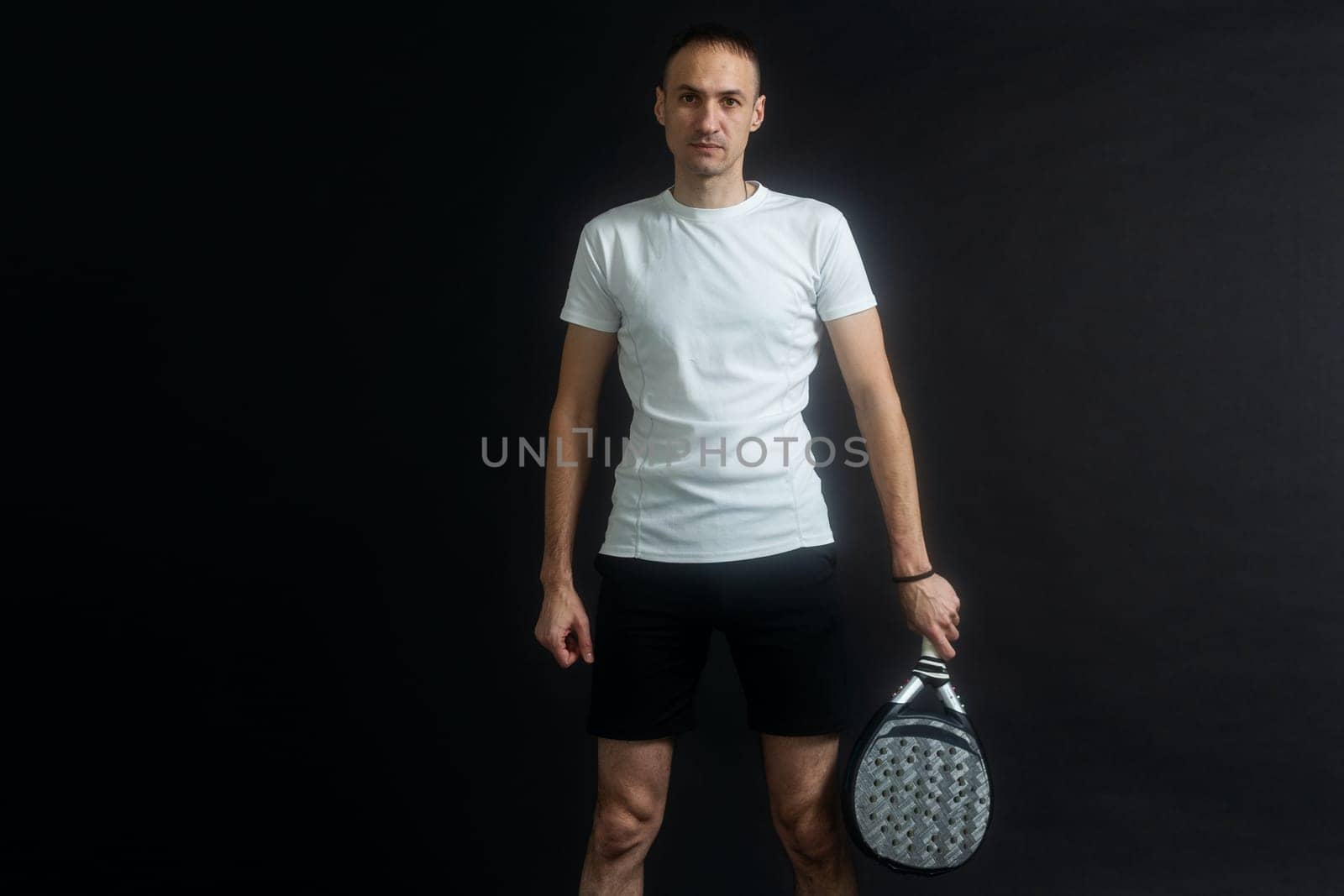 Beautiful man playing paddle tennis, racket in hand concentrated look. Young sporty boy ready for the match. Focused padel athlete ready to receive the ball. Sport, health, youth and leisure concept. High quality photo