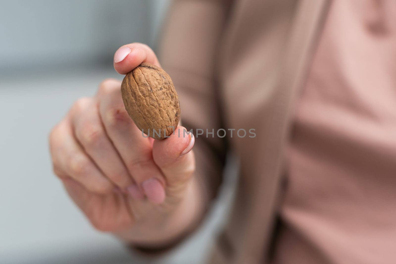 Beautiful female hand holding a walnut against a white background closeup. High quality photo
