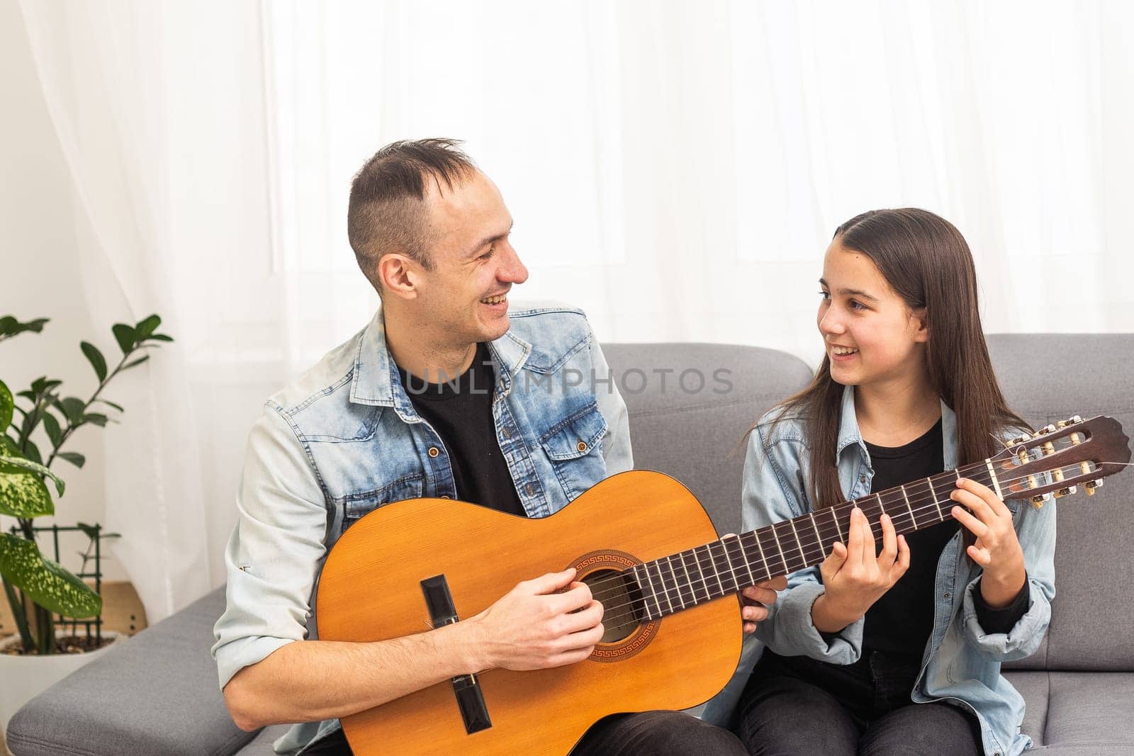 Artistic talented girl showing her latin music teacher the new song she learned to play on the acoustic guitar at home. High quality photo