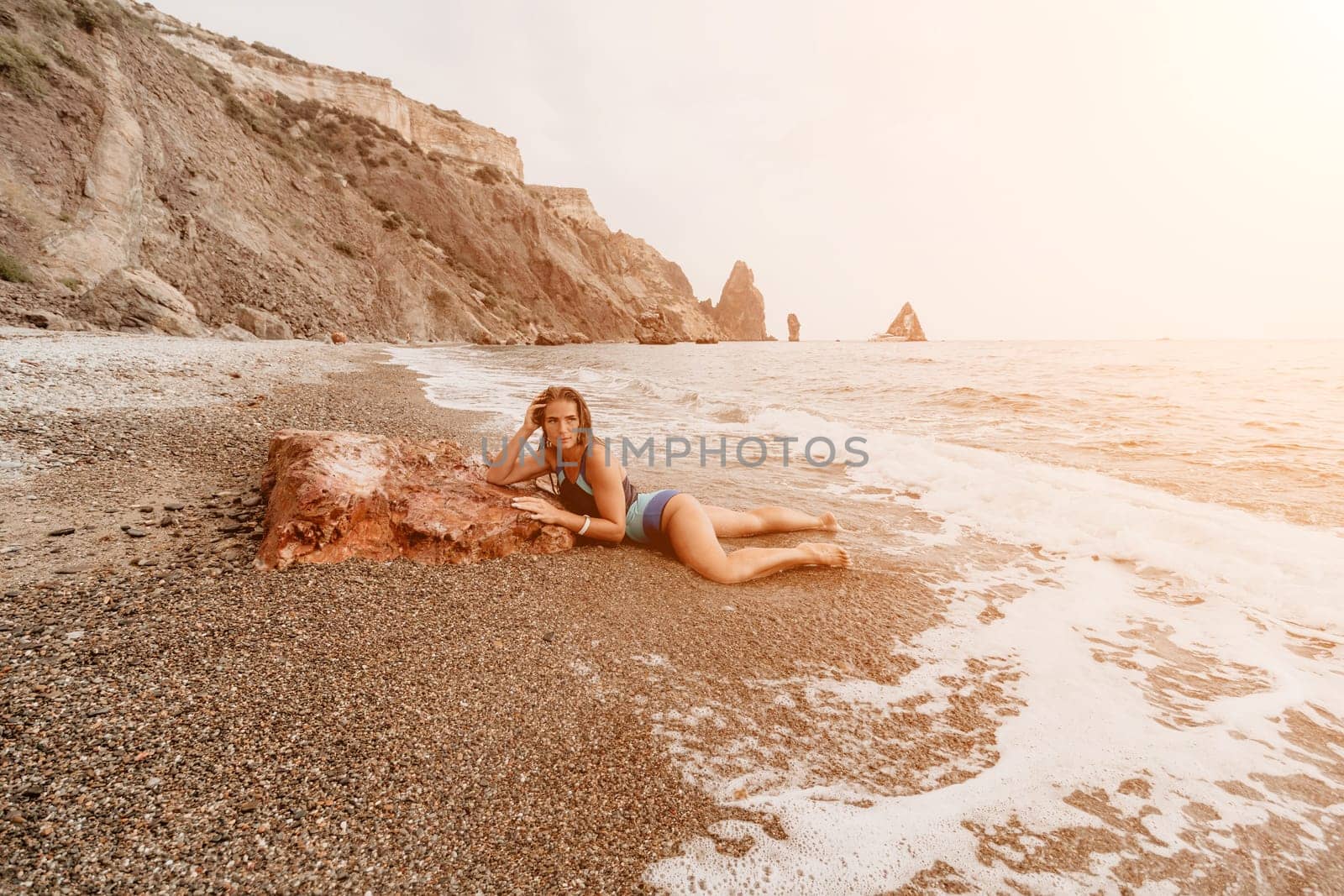 Woman travel sea. Young Happy woman in a long red dress posing on a beach near the sea on background of volcanic rocks, like in Iceland, sharing travel adventure journey