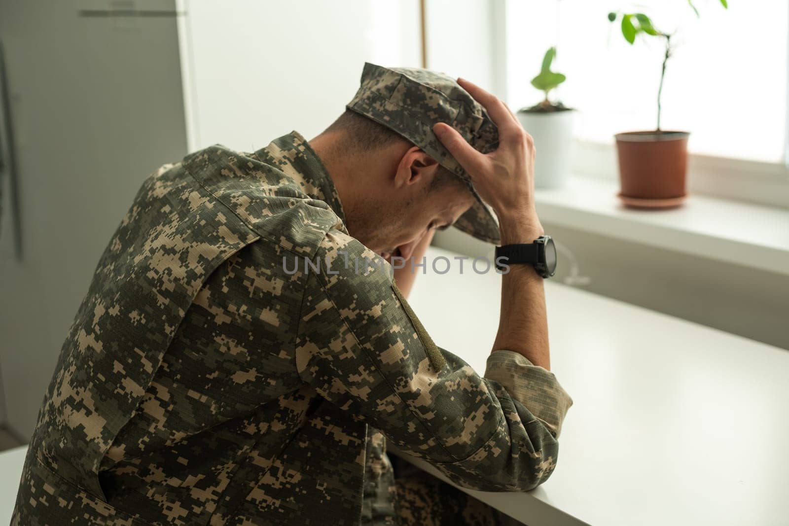 Depressed army man in uniform sitting in an empty room. Place for your poster on the wall. High quality photo