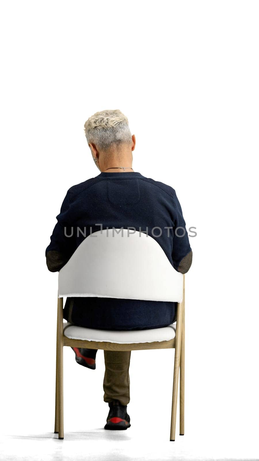 A man, full-length, on a white background, sitting on a chair.