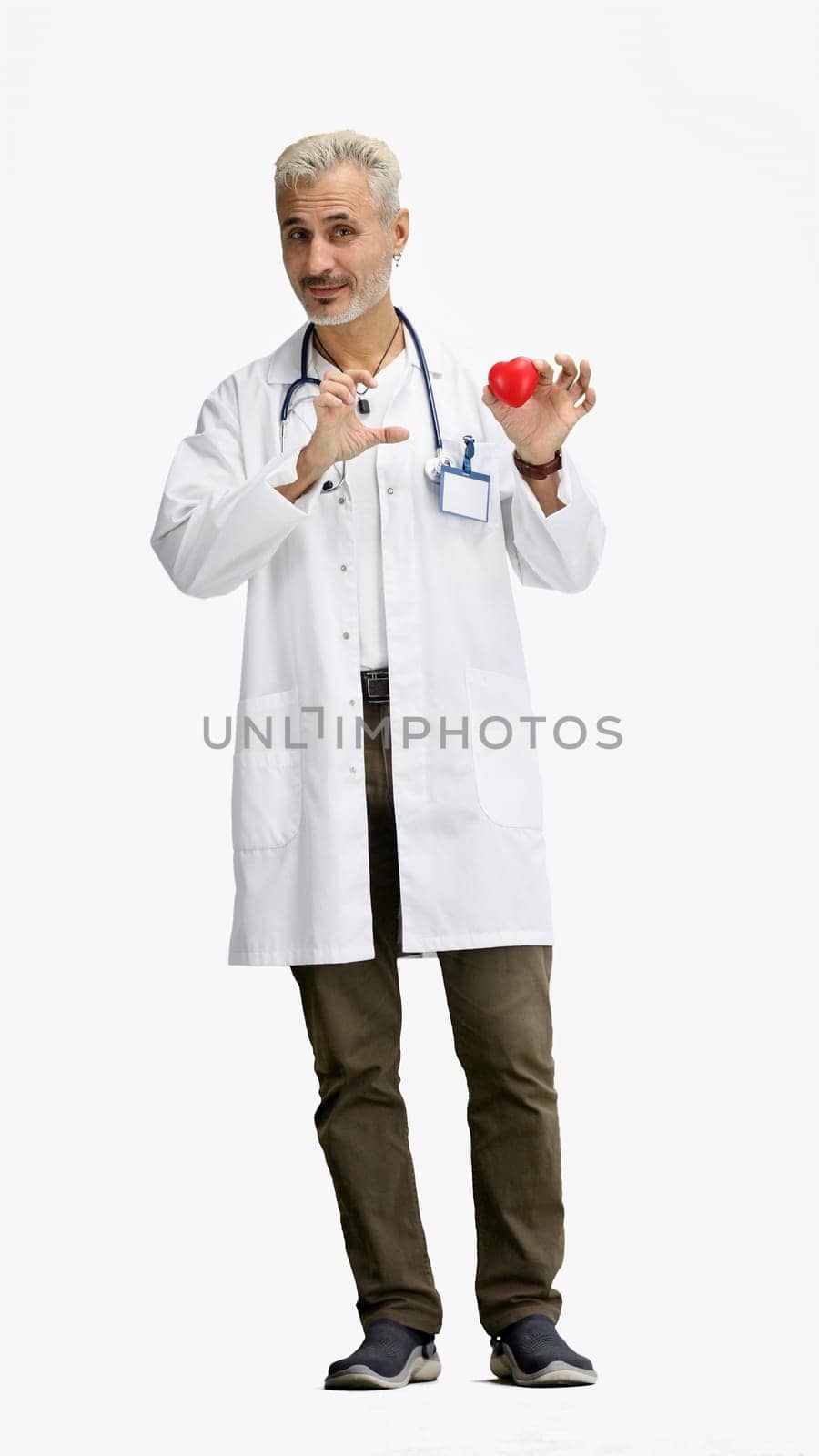 The doctor, in full height, on a white background, shows the heart.