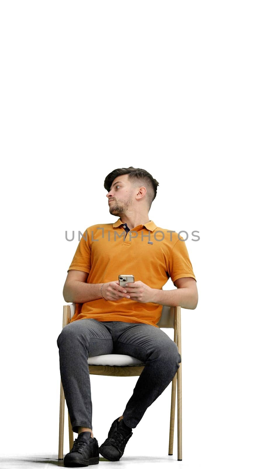 A man, full-length, on a white background, sitting on a chair.