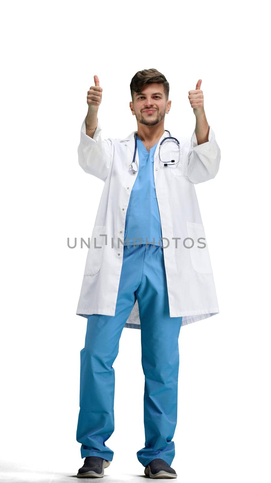 The doctor, in full height, on a white background, shows his thumbs up.