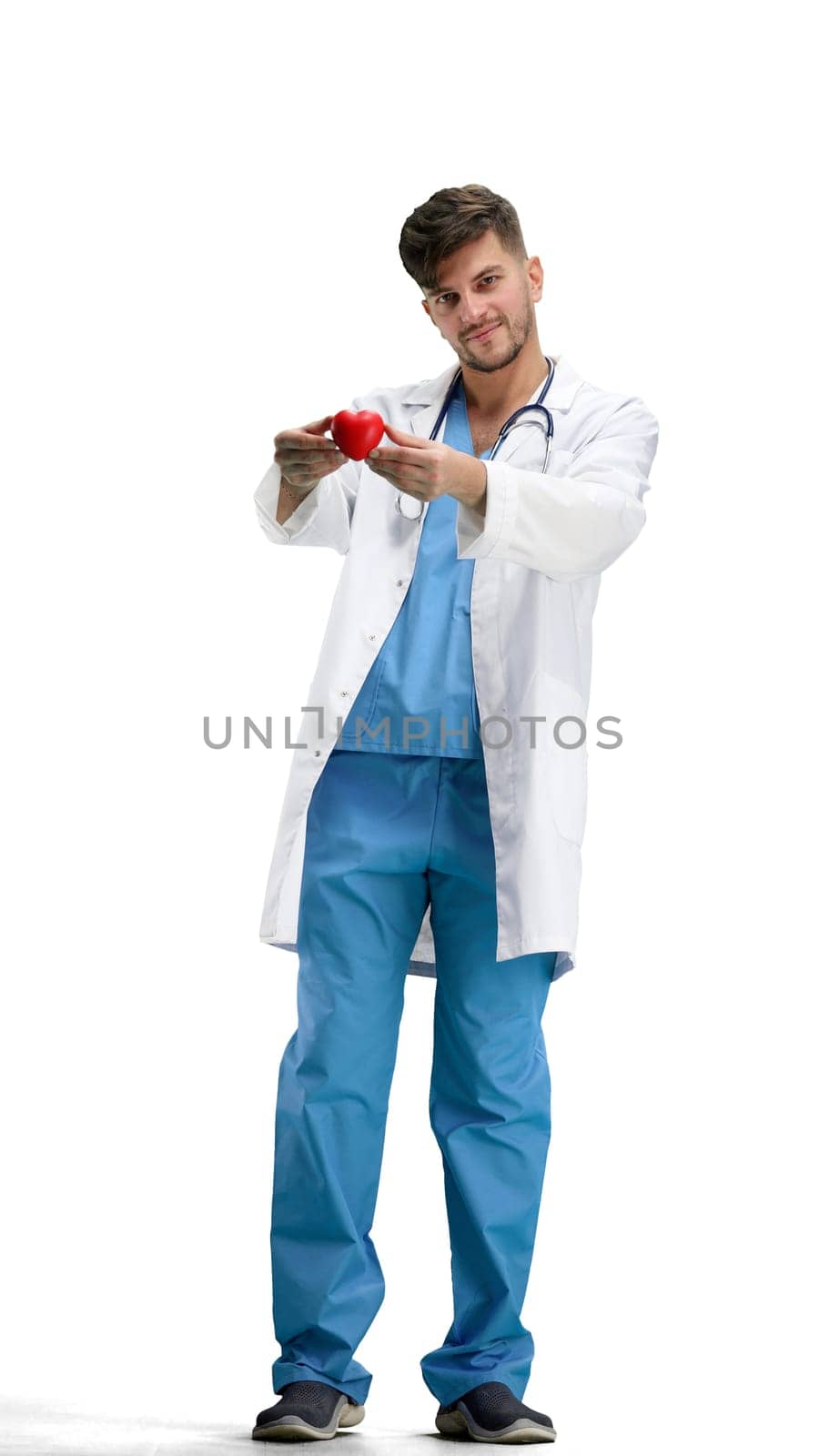 The doctor, in full height, on a white background, shows the heart.