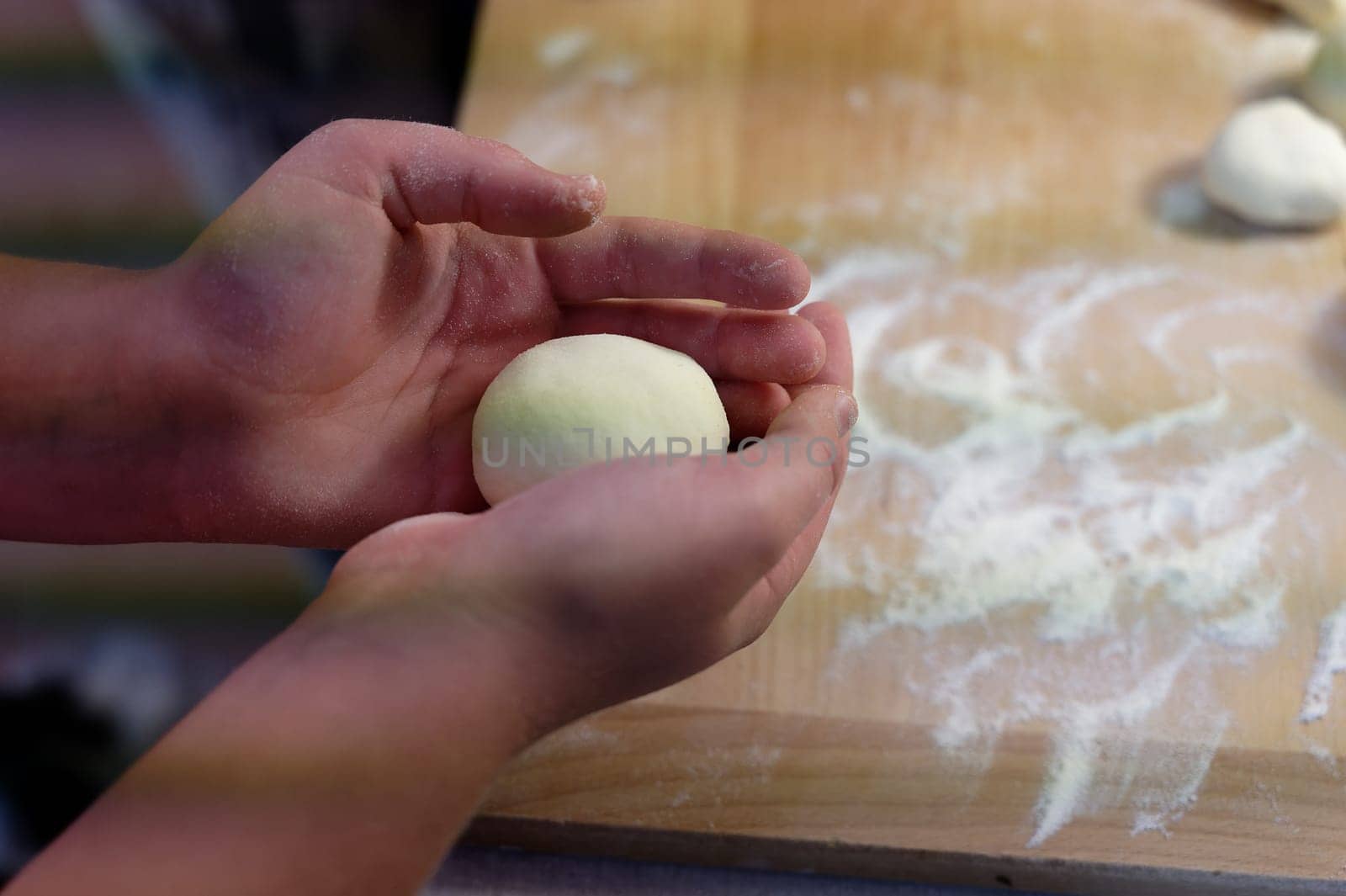 Preparation of homemade fruit dumplings with plums. Czech specialty of sweet good food. Dough on kitchen wooden table with hands. by Montypeter