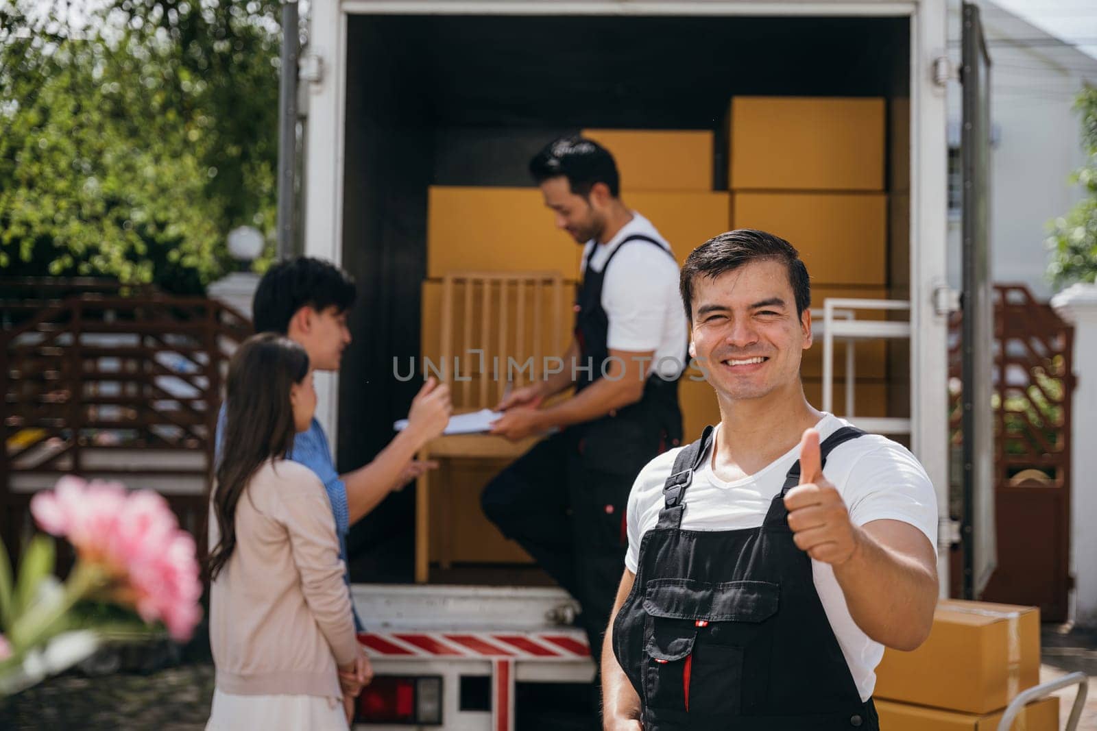 Portrait of a happy mover working unloading boxes into a new home from a truck. These removal company workers ensure smooth relocation spreading joy. Moving day concept by Sorapop