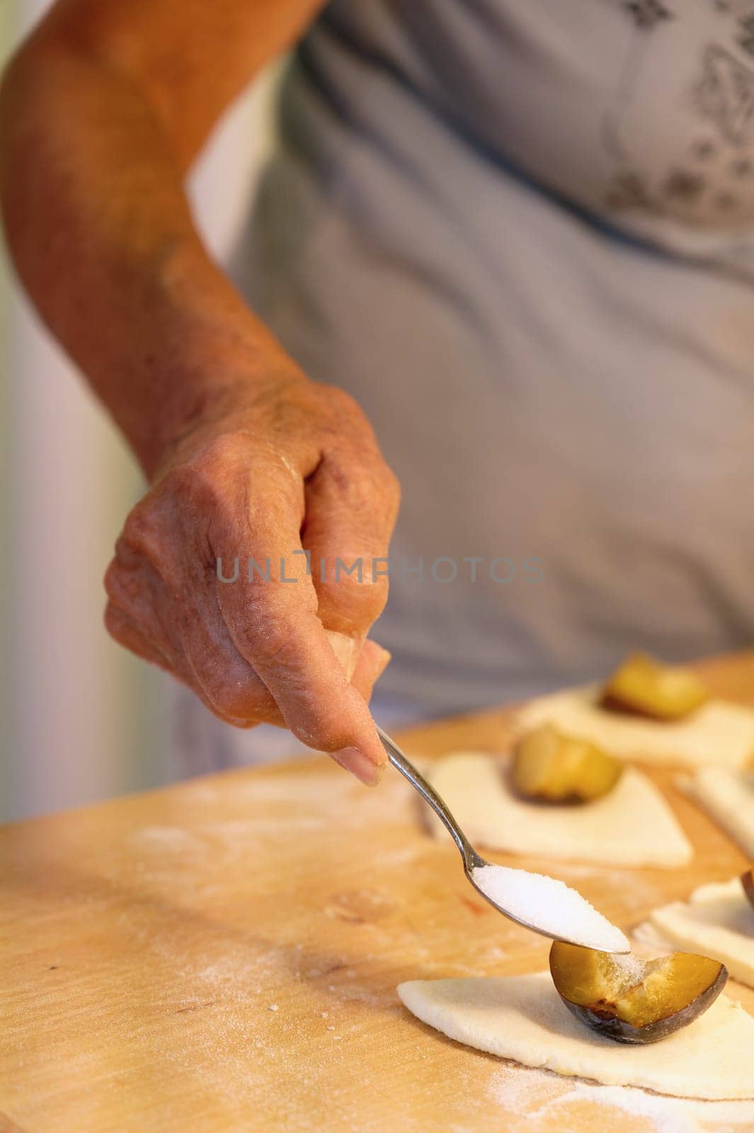 Preparation of homemade fruit dumplings with plums. Czech specialty of sweet good food. Dough on kitchen wooden table with hands.