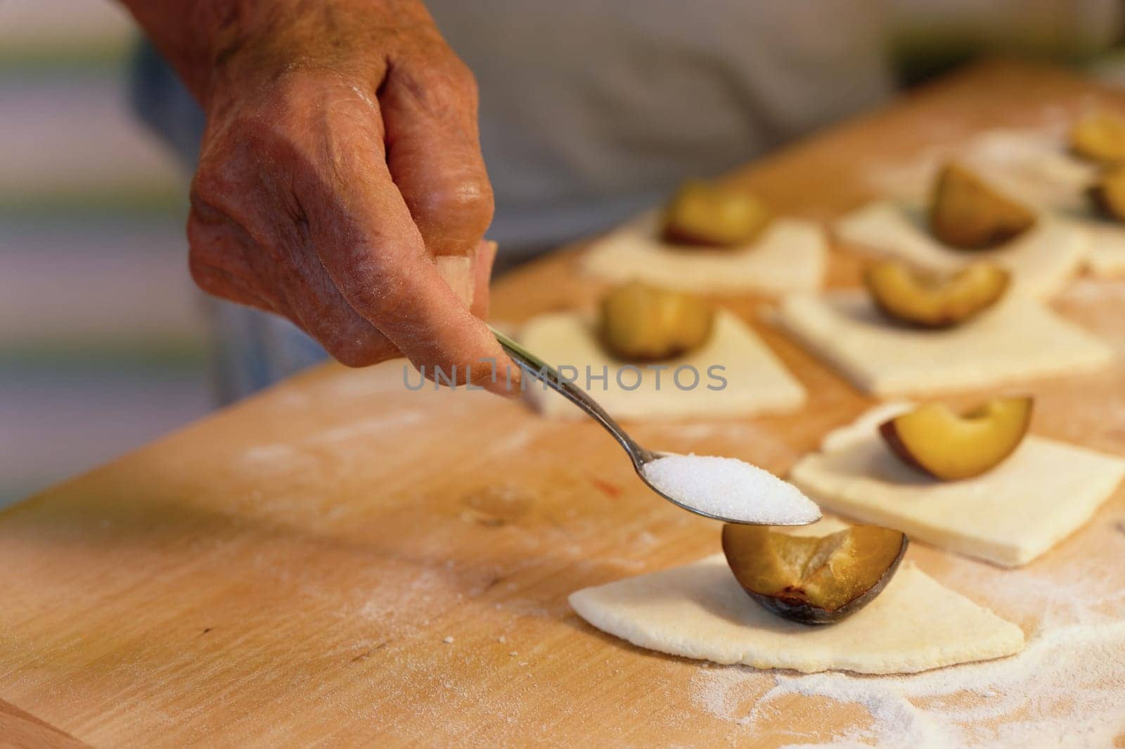 Preparation of homemade fruit dumplings with plums. Czech specialty of sweet good food. Dough on kitchen wooden table with hands. by Montypeter