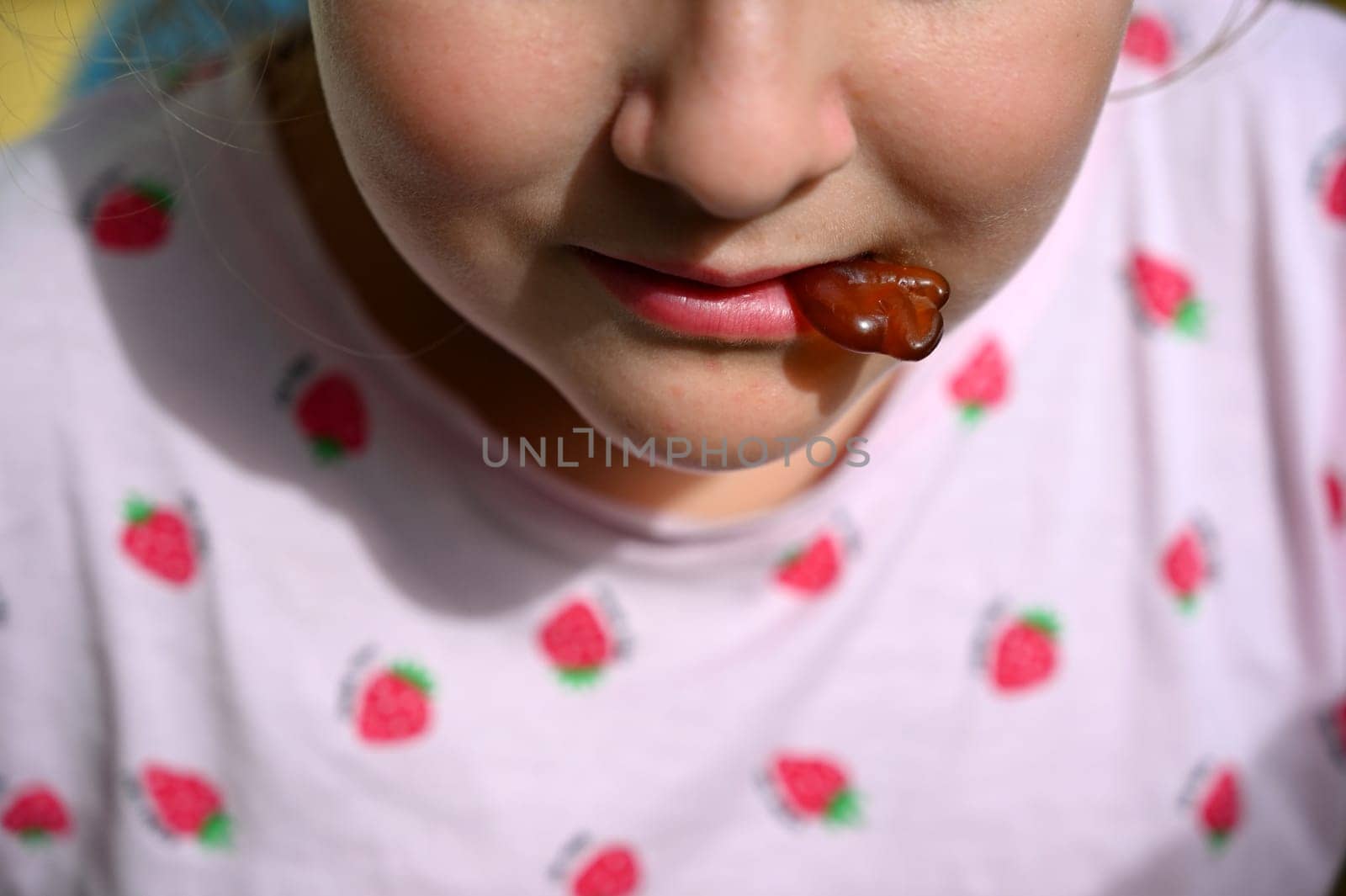Young girl - child eating candy and sweets. Detail of face and mouth. Concept for healthy lifestyle - healthy - unhealthy sweet food and sugar. by Montypeter