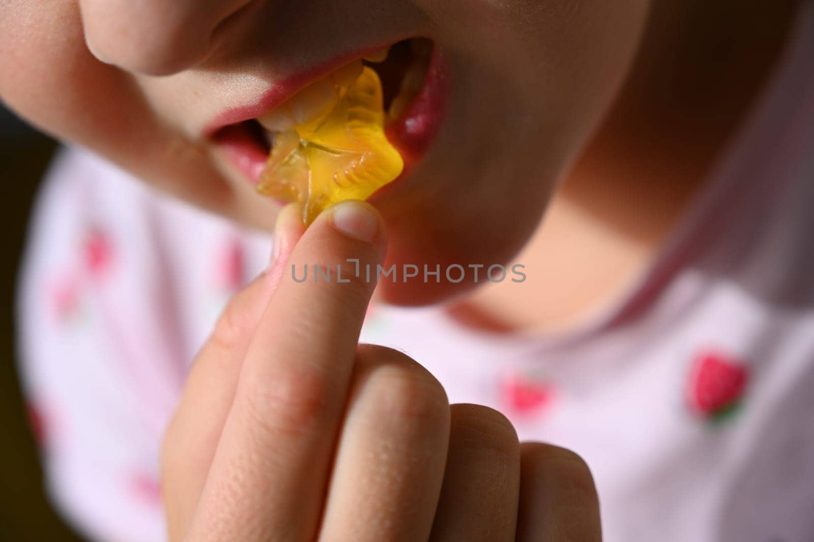 Young girl - child eating candy and sweets. Detail of face and mouth. Concept for healthy lifestyle - healthy - unhealthy sweet food and sugar. by Montypeter