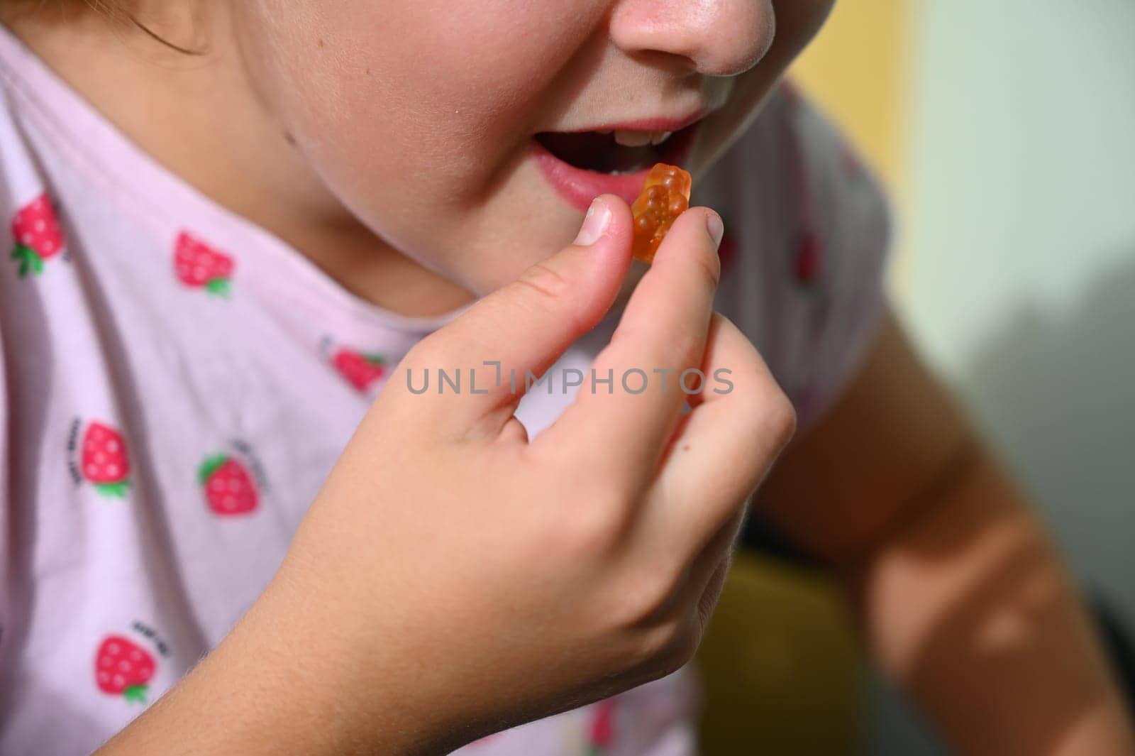 Young girl - child eating candy and sweets. Detail of face and mouth. Concept for healthy lifestyle - healthy - unhealthy sweet food and sugar.