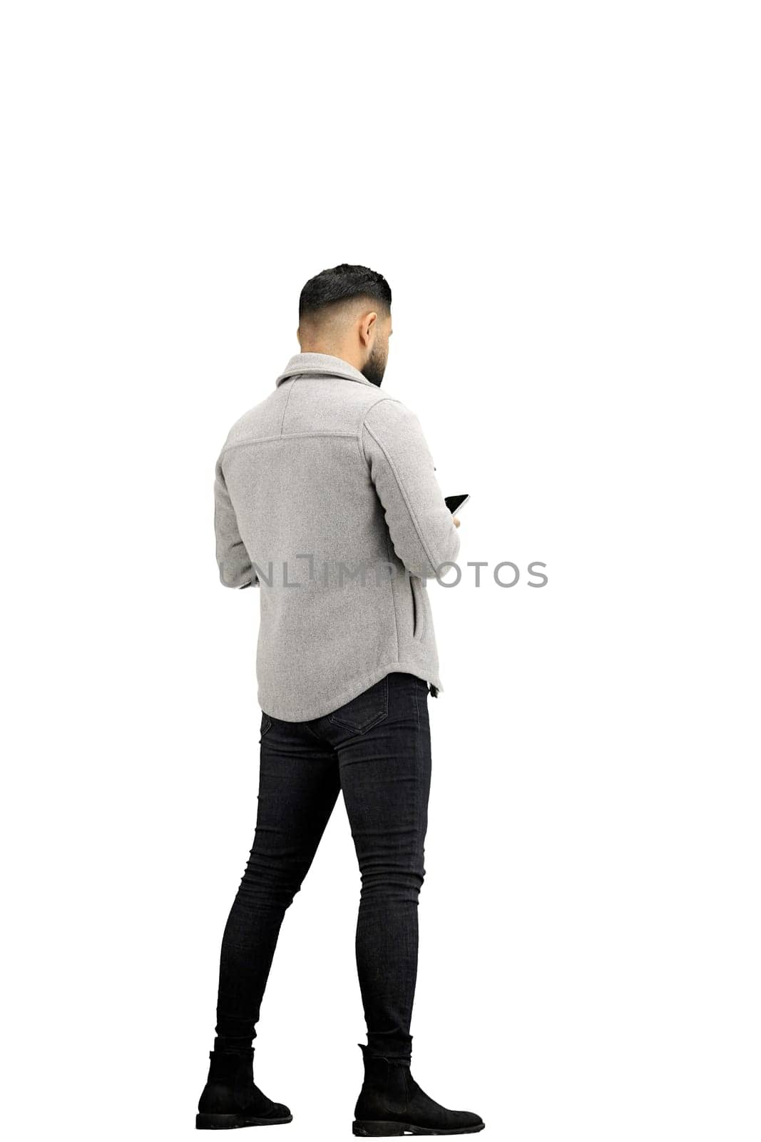 A man, full-length, on a white background, uses a phone.