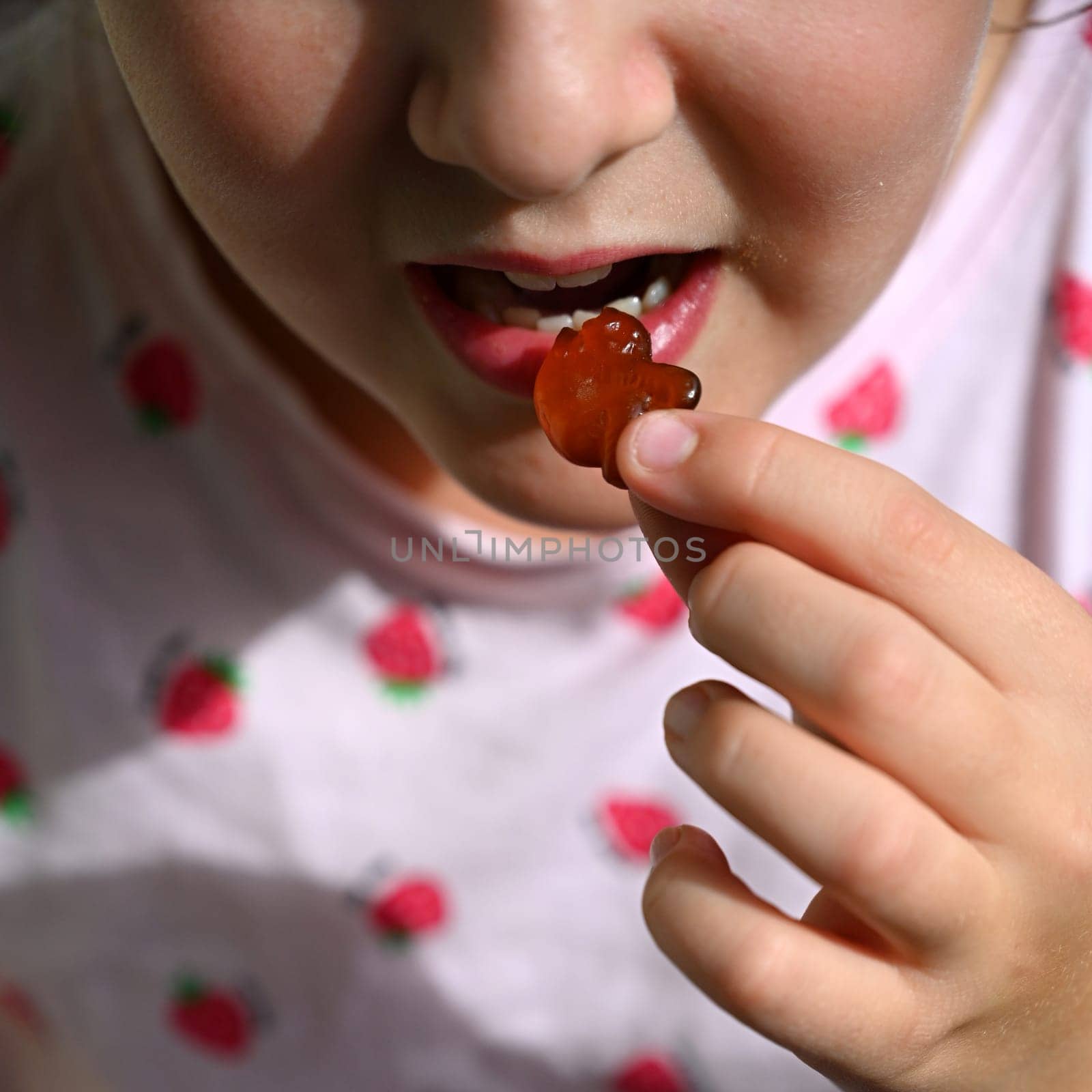 Young girl - child eating candy and sweets. Detail of face and mouth. Concept for healthy lifestyle - healthy - unhealthy sweet food and sugar. by Montypeter