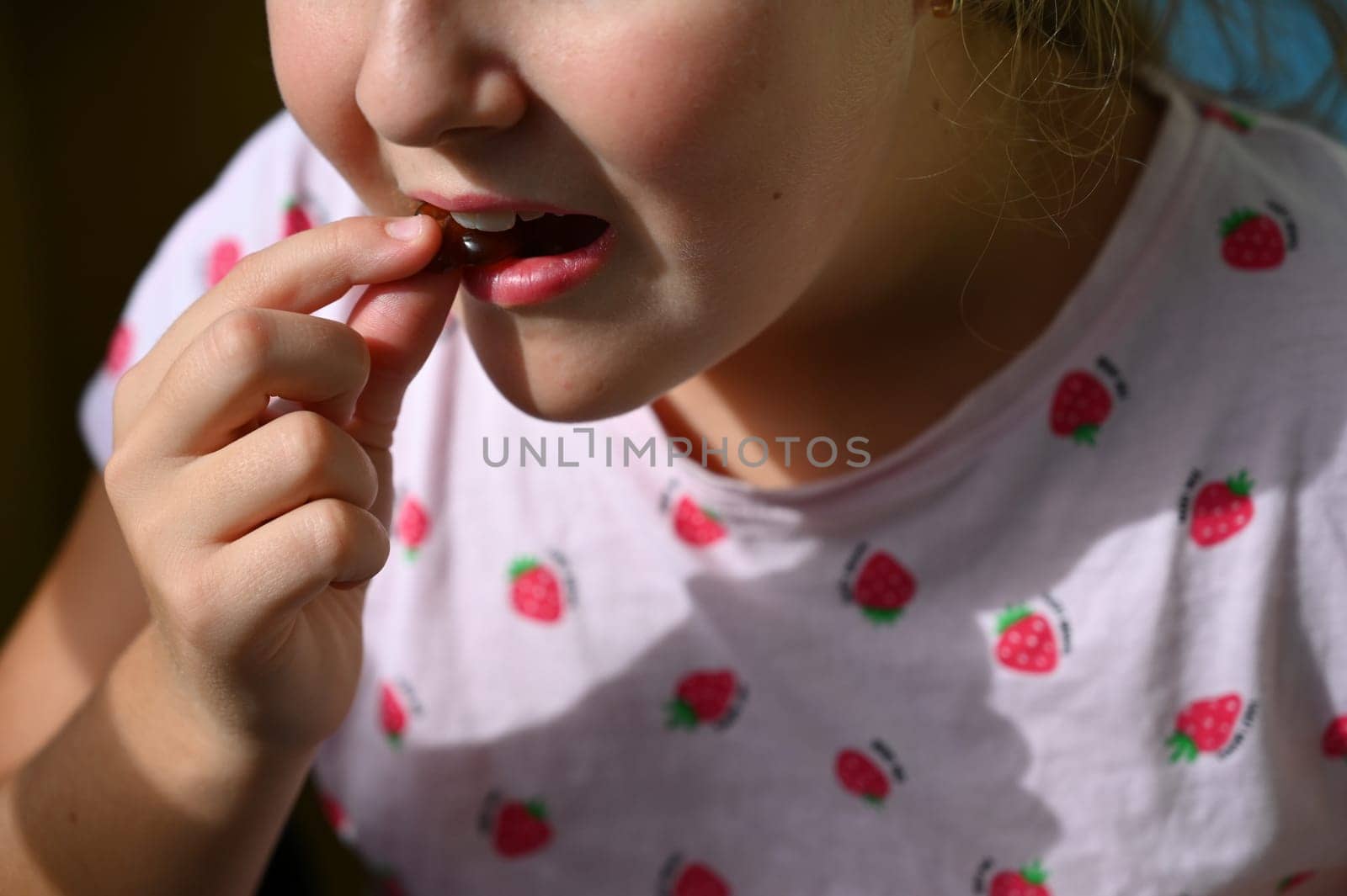 Young girl - child eating candy and sweets. Detail of face and mouth. Concept for healthy lifestyle - healthy - unhealthy sweet food and sugar. by Montypeter