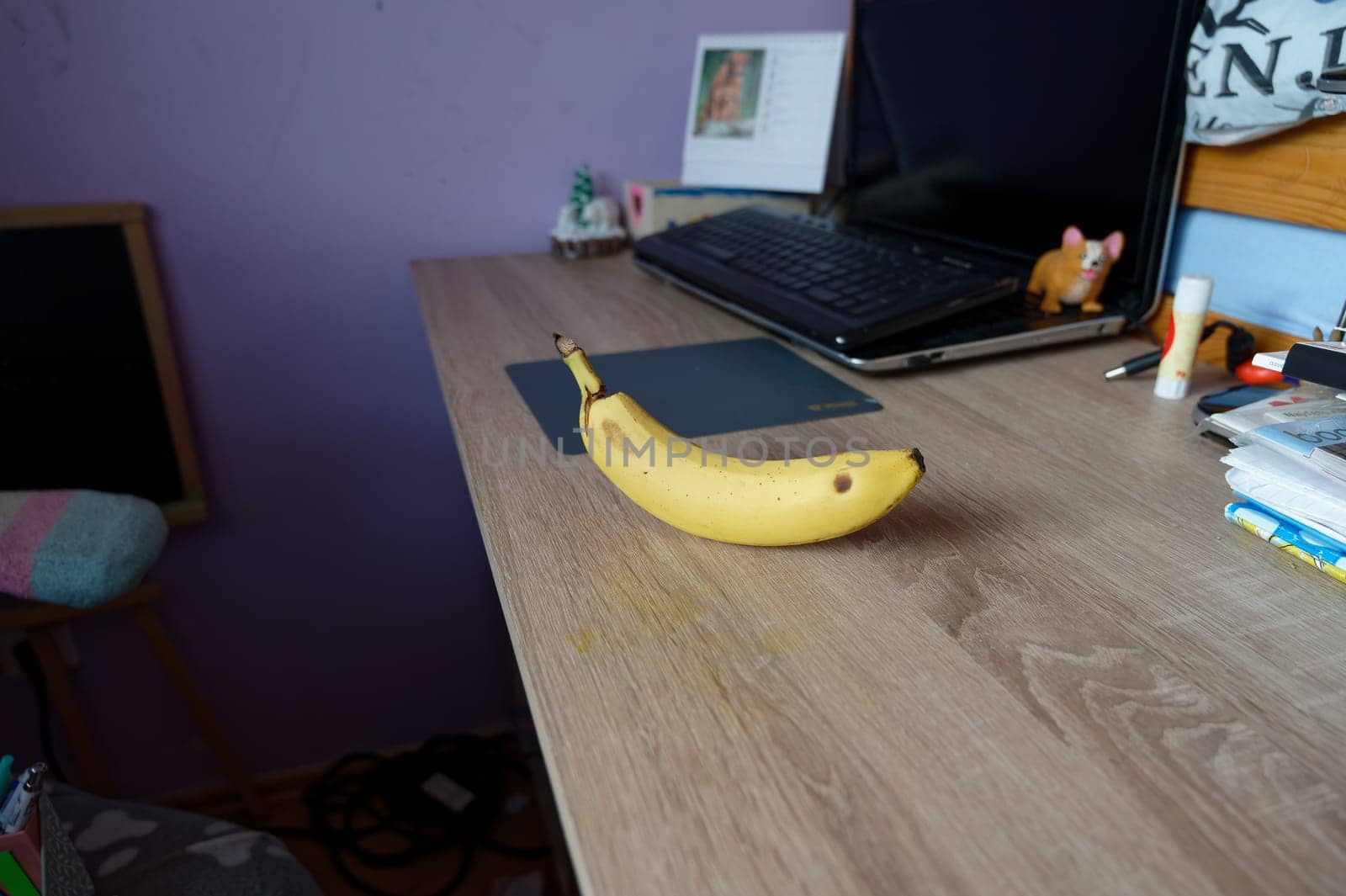 A beautiful fresh banana on a work table at home or in the office with a computer or laptop - notebook. by Montypeter