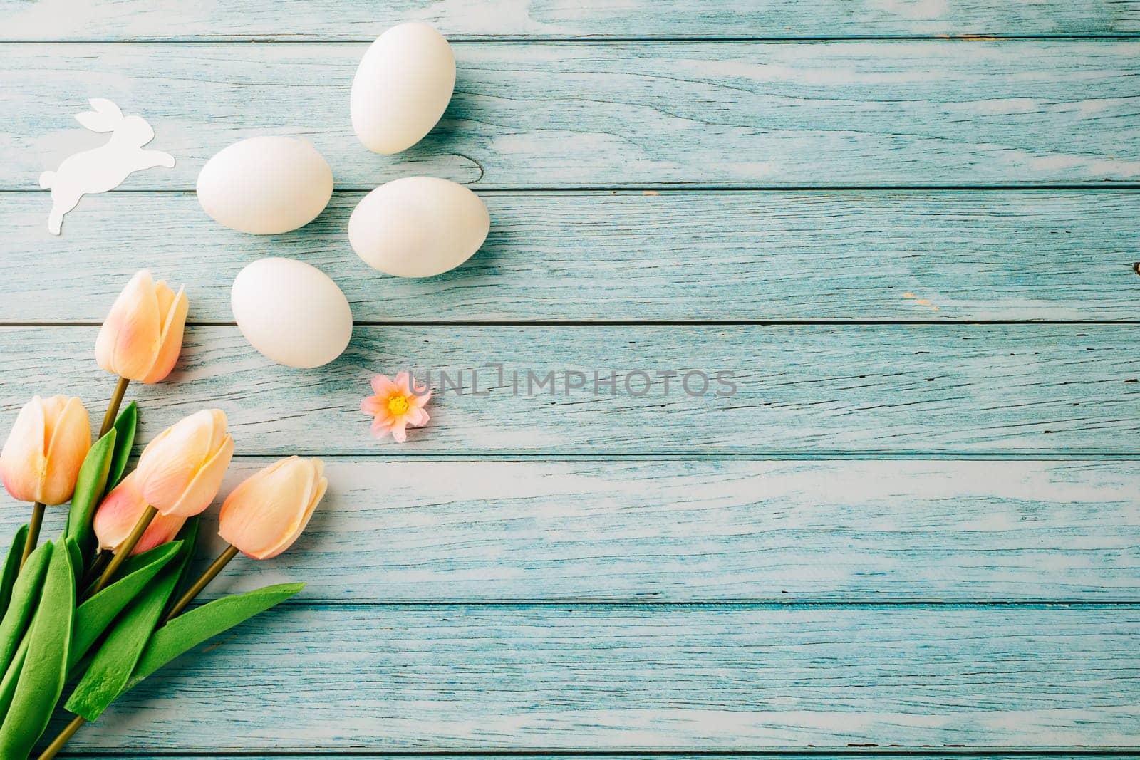 Happy Easter Day Concept. Flat lay of holiday banner background design white easter eggs and beautiful tulip flowers on blue wooden background with empty copy space, celebration greeting card