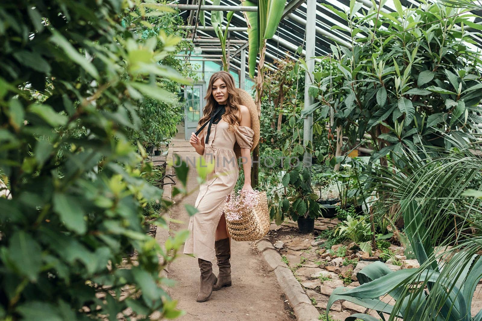 A beautiful young woman takes care of plants in a greenhouse. The concept of gardening and an eco-friendly lifestyle