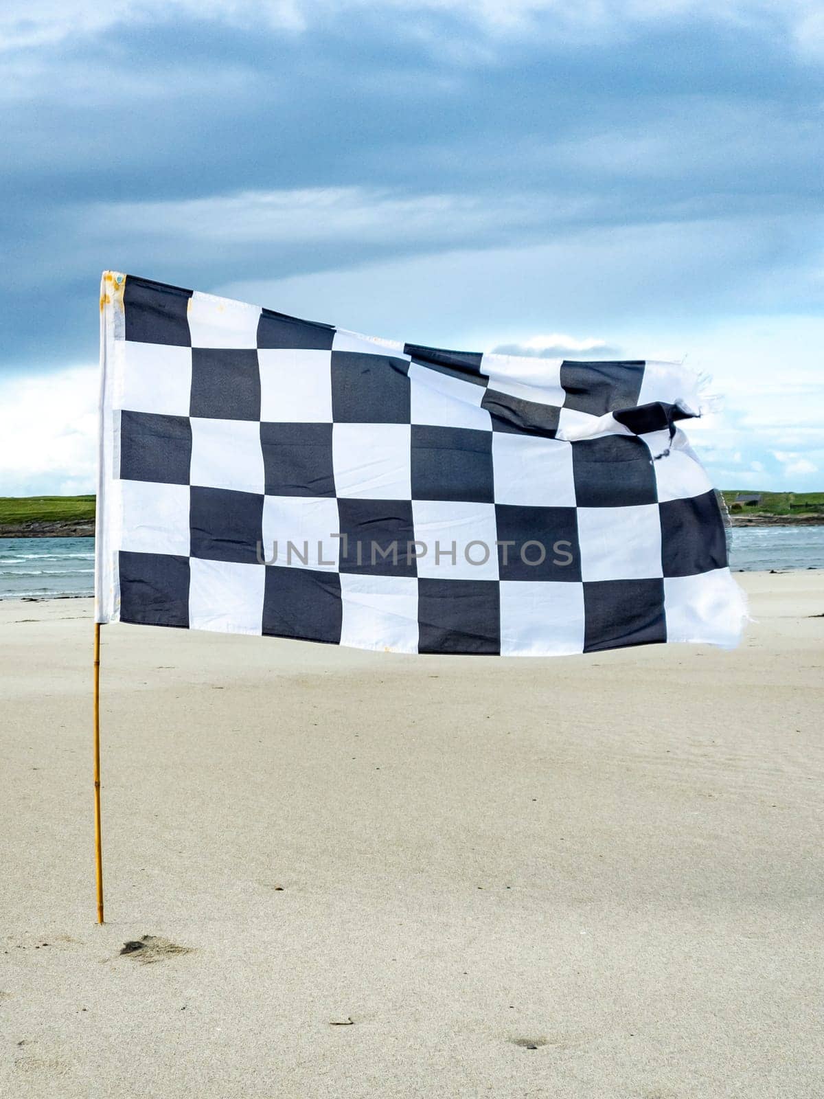 Black and white flag waving on the sandy beach.