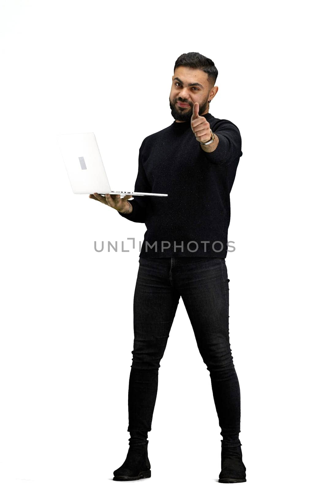 A man, in full height, on a white background, uses a laptop.