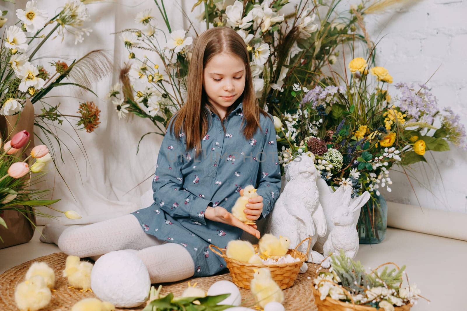 Two girls in a beautiful Easter photo zone with flowers, eggs, chickens and Easter bunnies. Happy Easter holiday. by Annu1tochka