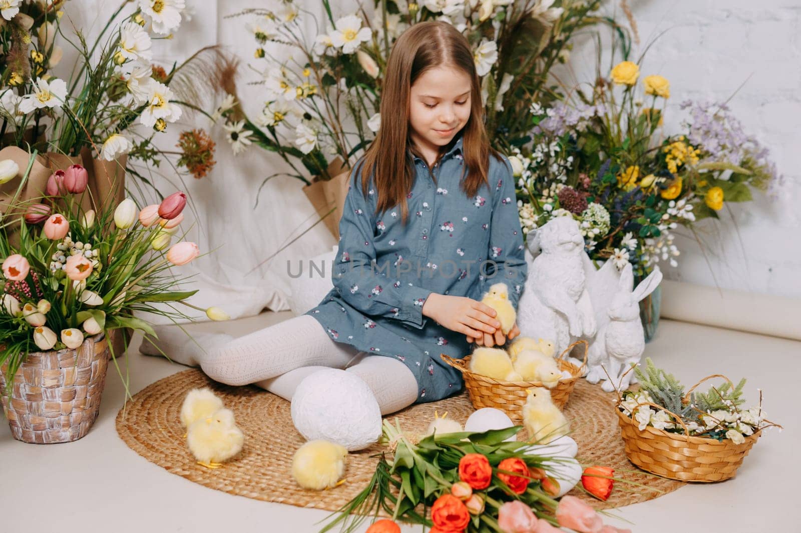 Two girls in a beautiful Easter photo zone with flowers, eggs, chickens and Easter bunnies. Happy Easter holiday