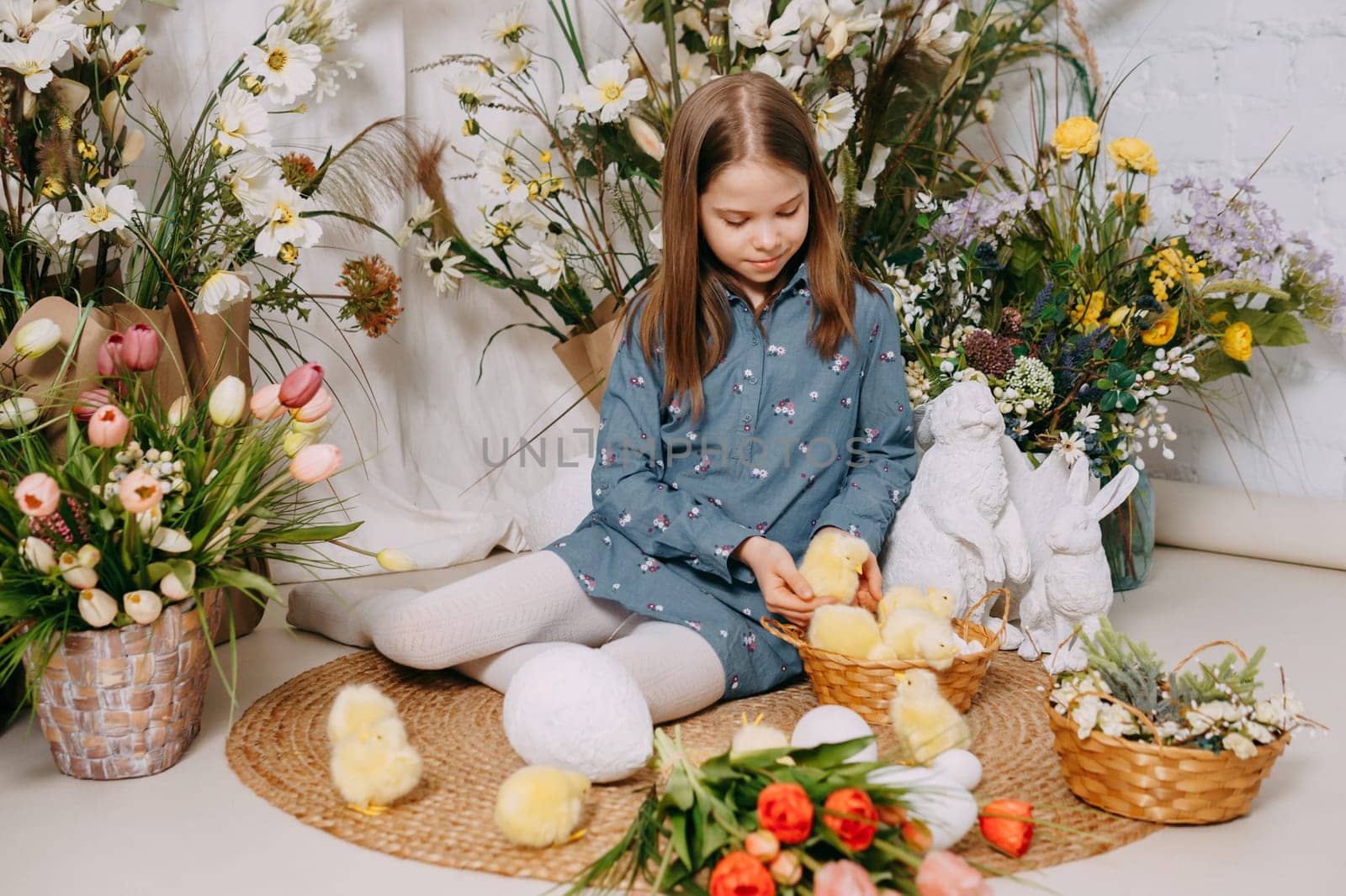 Two girls in a beautiful Easter photo zone with flowers, eggs, chickens and Easter bunnies. Happy Easter holiday