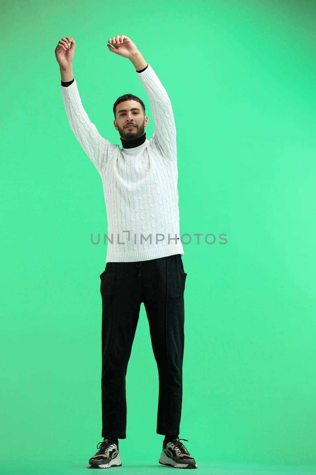 A man, full-length, on a green background, waving his arms.