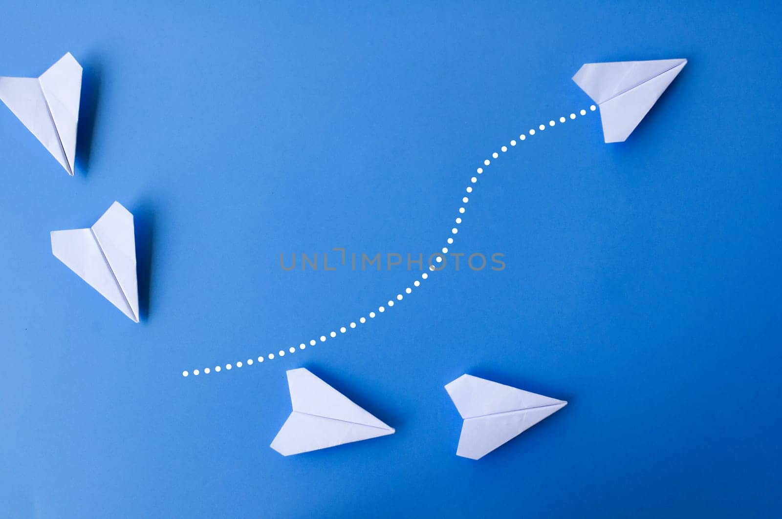 Top view of white paper airplanes with one flying at different direction