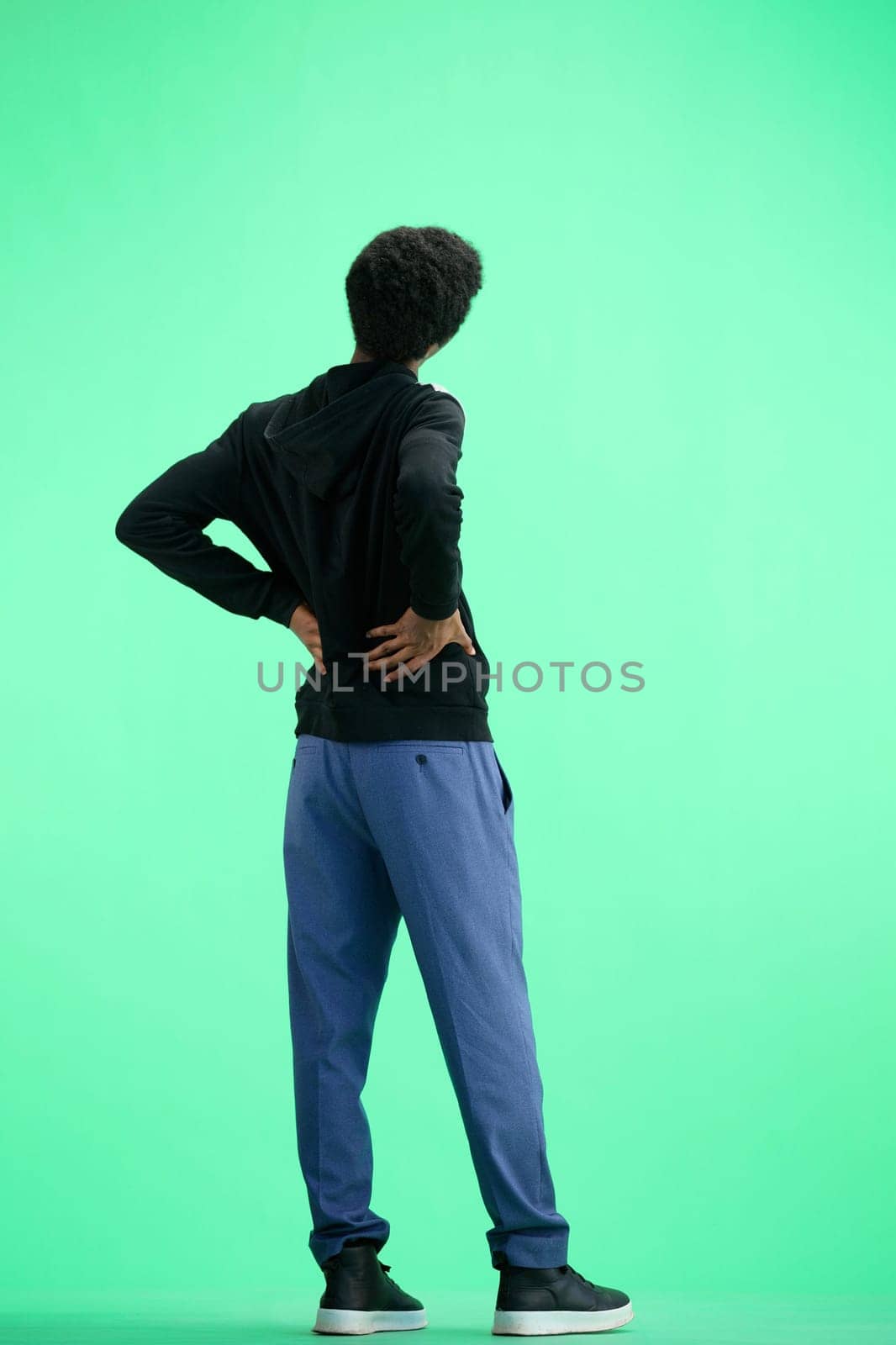 A man, full-length, on a green background, warming up.