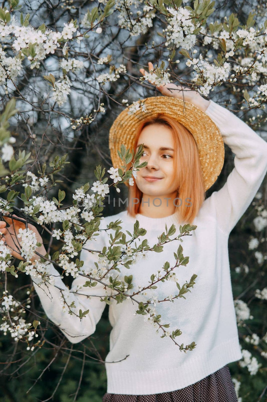 Portrait of a woman in a straw hat in a cherry blossom. Free outdoor recreation, spring blooming garden