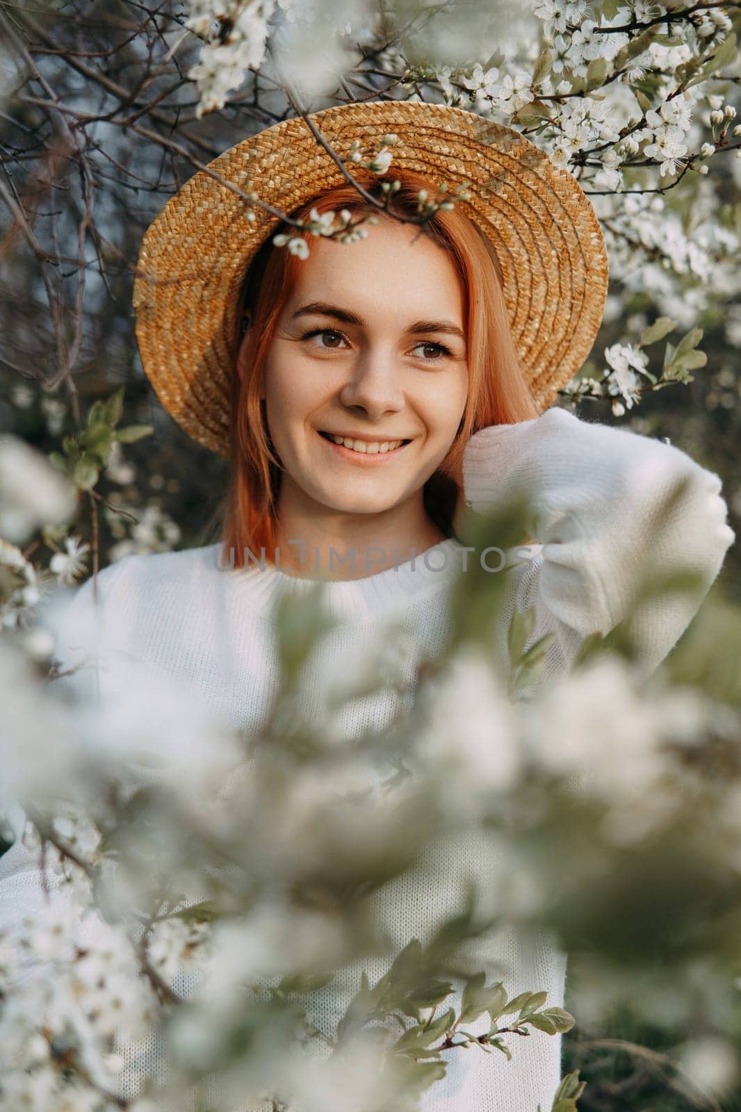Portrait of a woman in a straw hat in a cherry blossom. Free outdoor recreation, spring blooming garden