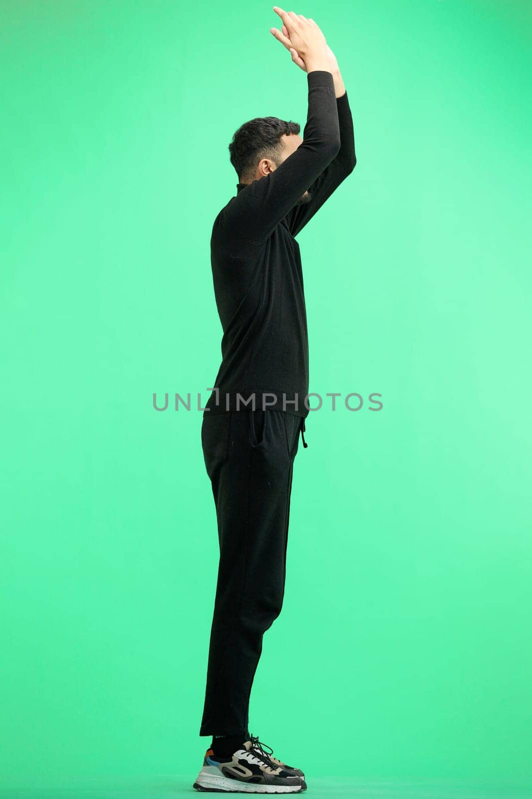 A man, full-length, on a green background, claps.