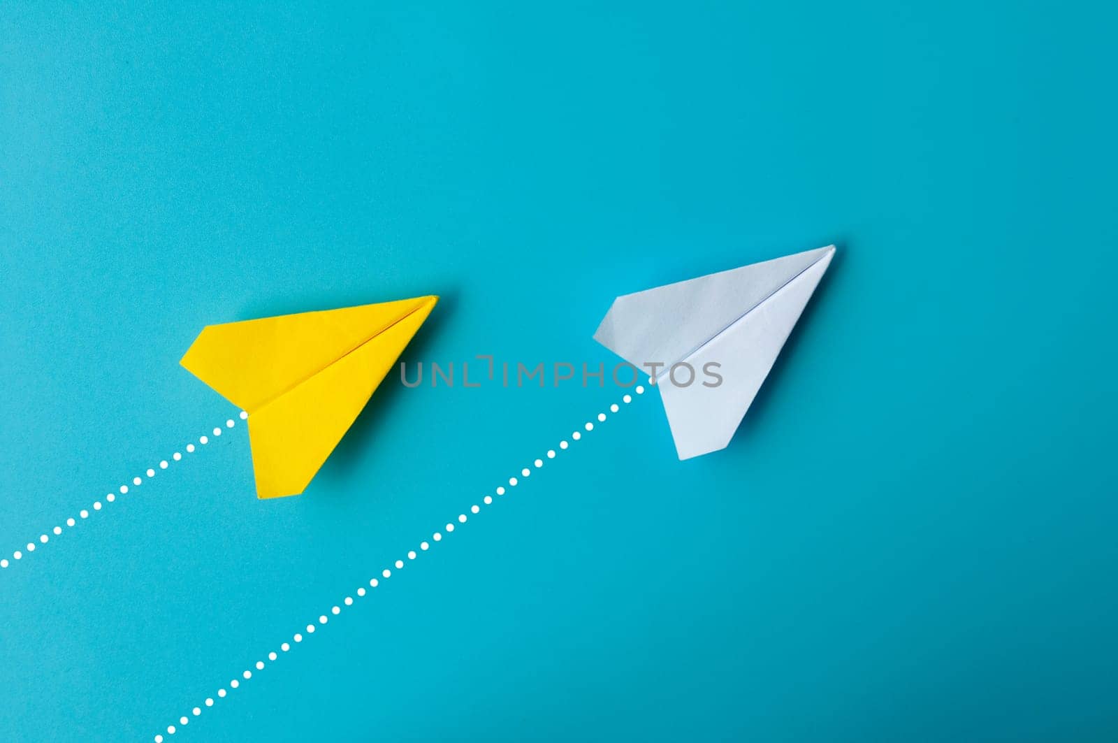 Top view of paper airplane - Yellow and white paper airplane origami flying to a same direction on blue background