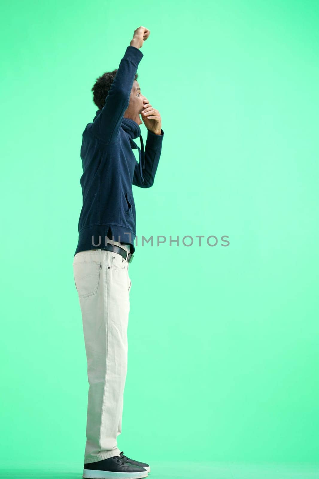 A man, full-length, on a green background, rejoices.