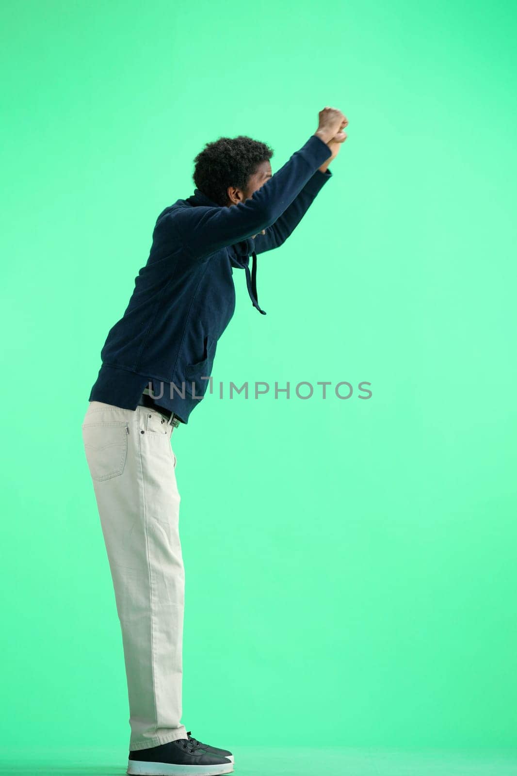 A man, full-length, on a green background, raised his hands up by Prosto