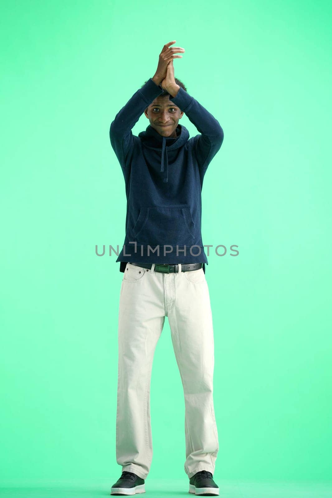 A man, full-length, on a green background, claps.