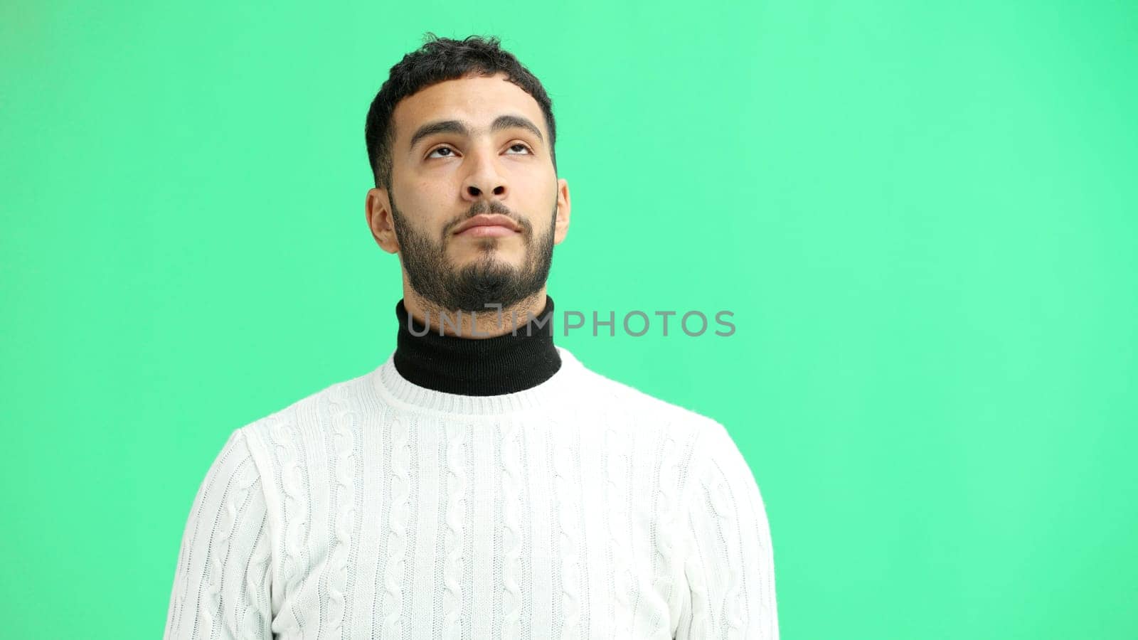 Man, close-up, on a green background, pointing up.