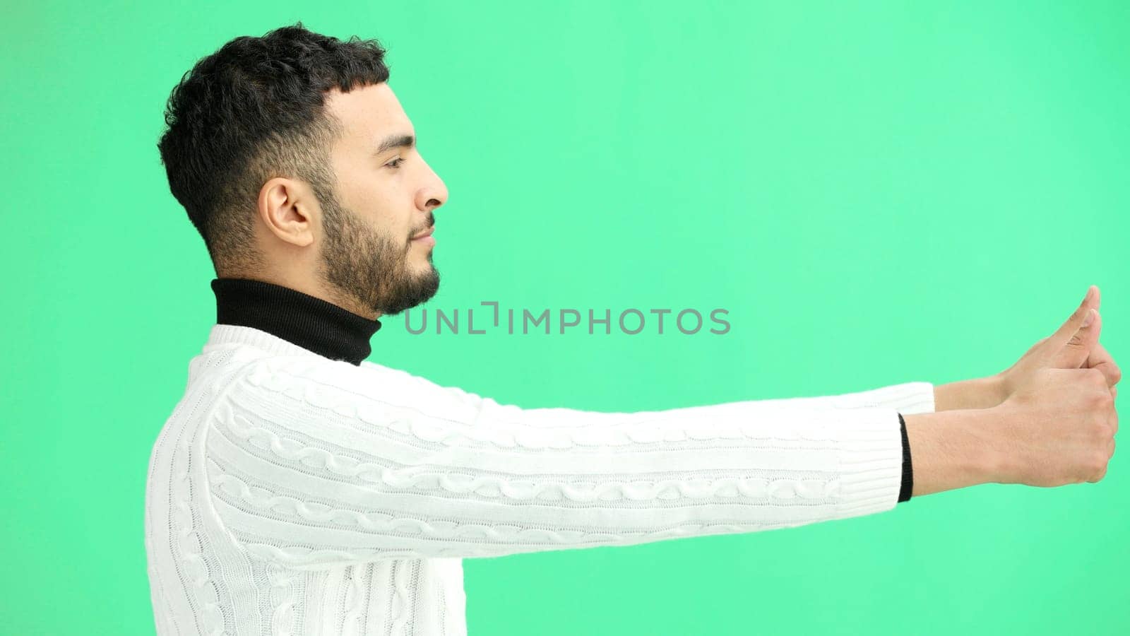 A man, close-up, on a green background, shows his thumbs up.