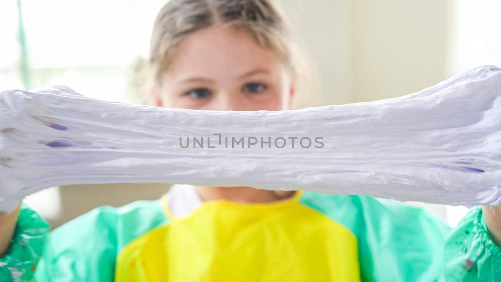 In a modern kitchen, a homeschooled girl is engrossed in creating homemade slime, a fun and educational hands-on project that enhances her creativity and problem-solving skills.