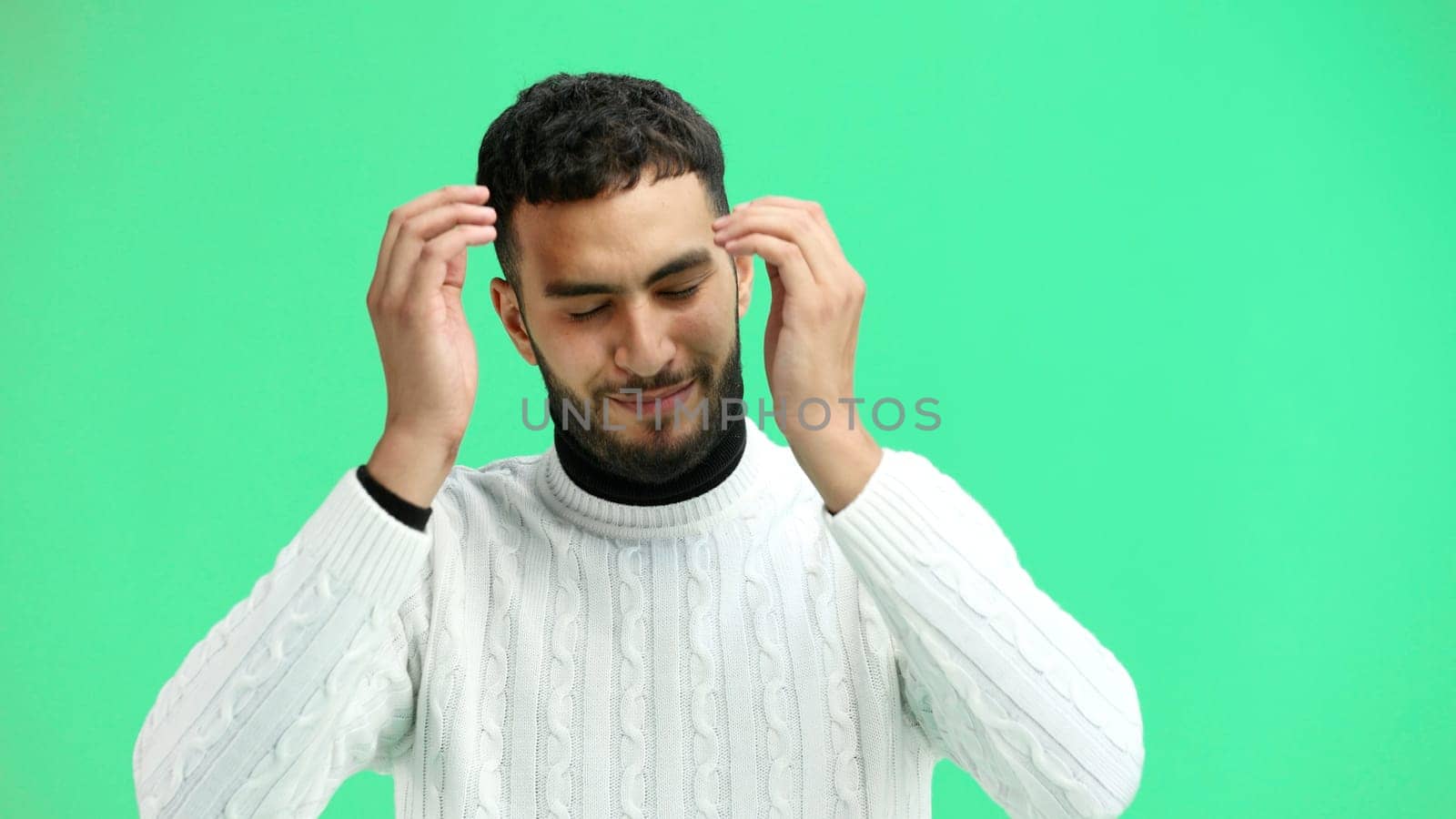 A man, close-up, on a green background, clutched his head.