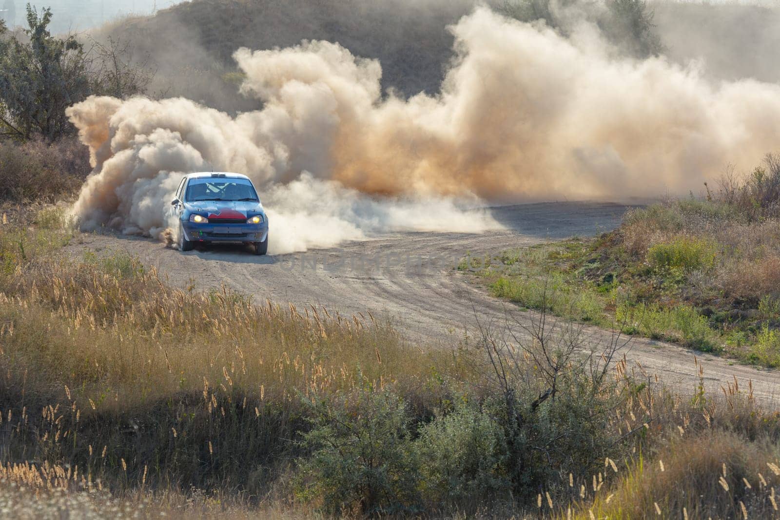 Sunny summer day. Dusty rally track. A rally car makes a lot of dust in a turn 17